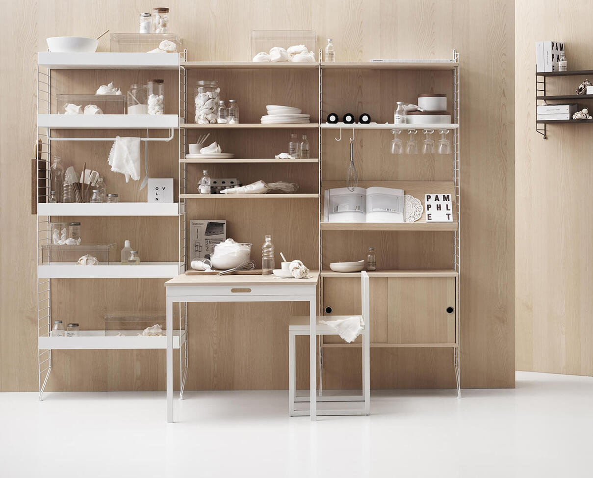 Wei&szlig;es String-Regal in der K&uuml;che mit Vitrinenschrank und Regalboden in Esche.