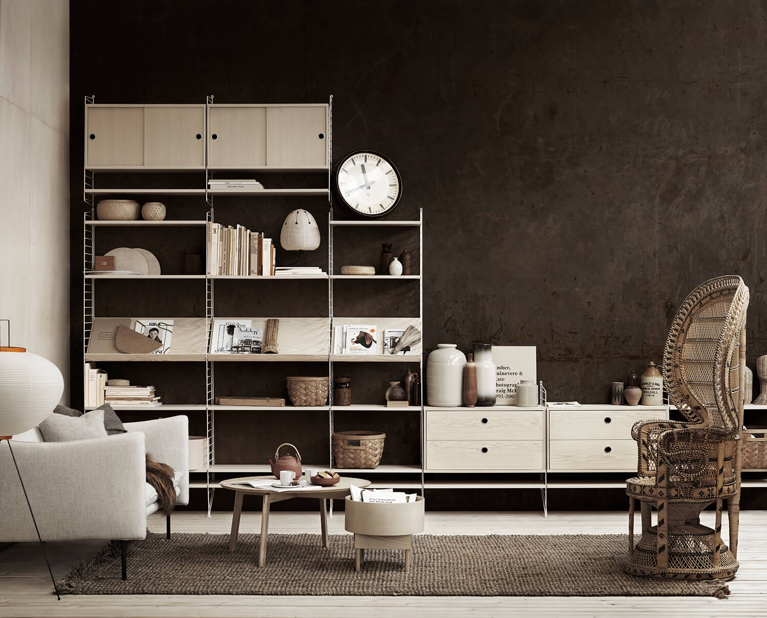 Beispiel für Inspiration bei der Einrichtung eines String-Regals im Wohnzimmer. String-Regal mit Zeitschriftenfächern, Regalböden und Schrank aus Esche vor dunkelbrauner Wand.