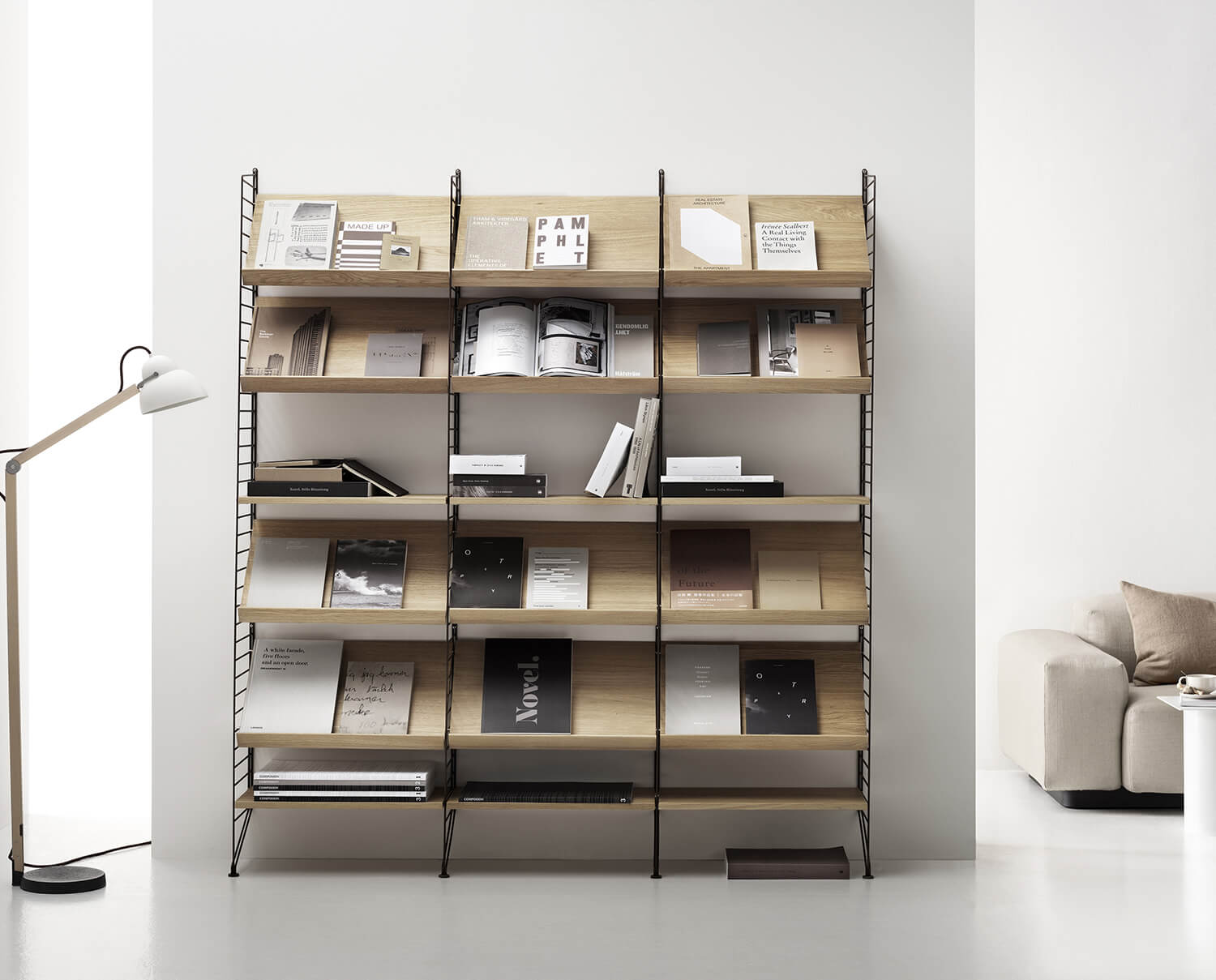 String B&uuml;cherregal mit Zeitschriftenf&auml;chern in Esche in einem wei&szlig;en Wohnzimmer mit passender Einrichtung.